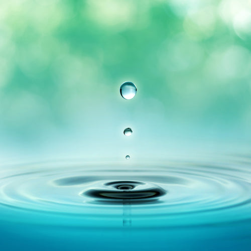 close up of three droplets in a blurred green background