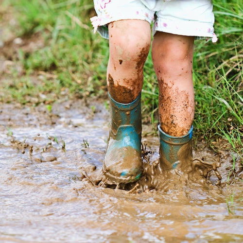Childs feet stomping in a mud puddle.