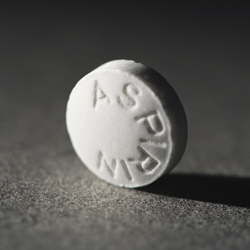 Close up of round white aspirin pill standing on side.