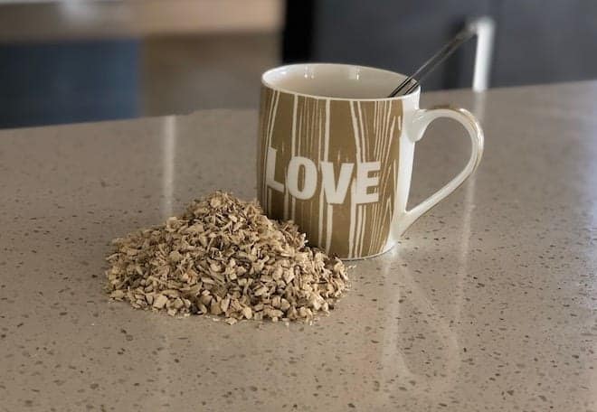 Marshmallow root tea in a pile beside a mug with love written on it