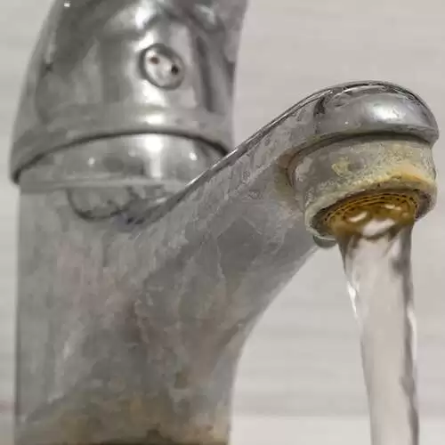 Hard water flows from an old tap aerator.