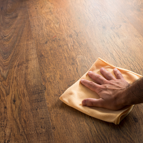 rubbing polish on hardwood floor with a cloth.