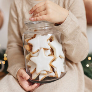 holding glass jar with christmas cookies star shape.